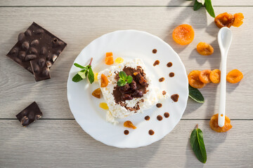 Healthy cottage cheese dessert with dried apricots, candied fruits and chocolate syrup