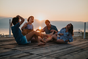 A joyful gathering of young friends enjoying music and laughter by a serene lakeside during a picturesque sunset. A moment of connection, fun, and memorable experiences in nature.