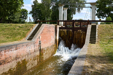 Sluice water channel containing sluice gate, type of lock to manage the water flow and water level. Mill race, leet, flume, penstock or lake is a sluice channeling water toward water mill.