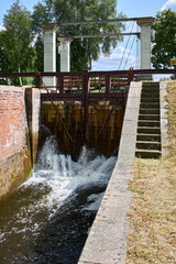 Obraz premium Sluice water channel containing sluice gate, type of lock to manage the water flow and water level. Mill race, leet, flume, penstock or lake is a sluice channeling water toward water mill.
