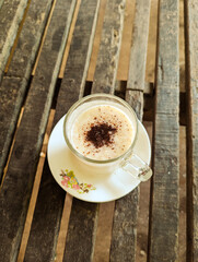 a cup of light cream colored drink on a white cup saucer with pink, yellow and blue flower decorations