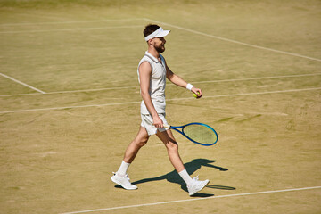 Handsome man enjoys a summer tennis match in white sportswear on the court