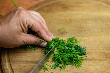 Woman cutting green dill on the cutting board