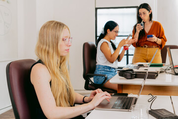 In a relaxed coworking space, young Latin women work with their laptops