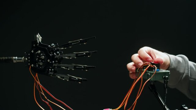 Modern Robotic Arm Holding and Moving, man working with Mechanical components, Engineers Using Tablet Computer to Manipulate and Program the Robot.