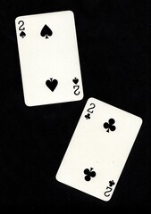A pair of playing cards of the same value isolated on a black background.