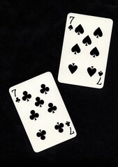 A pair of playing cards of the same value isolated on a black background.