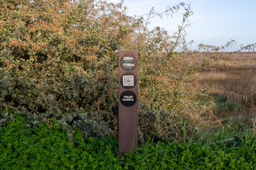 Hiking trail sign showing distances and qr code in riverside park of tagus estuary, lisbon, portugal