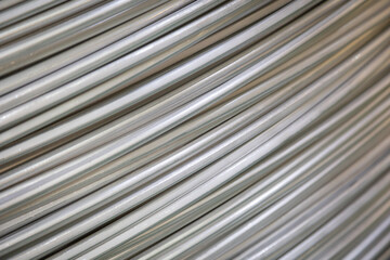Close-up of coiled aluminum wires, highlighting their smooth surface and layered overlapping pattern, captured in soft lighting..
