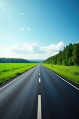 Fototapeta premium Asphalt Road Stretching Towards a Lush Green Field Under a Bright Blue Sky with Fluffy White Clouds