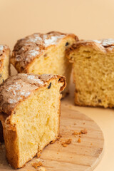 Panettone cake with raisins and candied fruit, sweet traditional Italian pastry on beige background. Easter cake or Christmas pastry cut in a half.