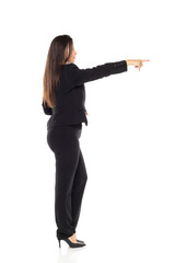 Professional businesswoman in black suit pointing forward with authority, full-length profile view against white background showing leadership and direction.