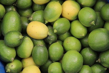 Close up of fresh vibrant green limes and yellow lemon fruit in market place