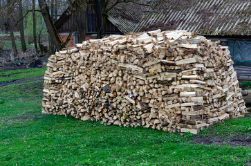 Firewood stacked in spring in a rural area for winter heating – traditional countryside preparation for cold season