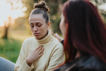 A young woman appears emotionally distressed while her friend comforts her in a scenic outdoor...