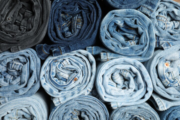 Different stylish rolled jeans as background, top view