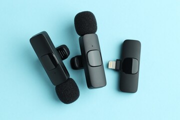 Lavalier microphones and wireless receiver on light blue background, flat lay