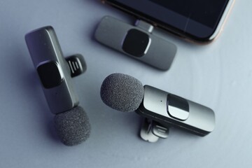 Lavalier microphones and smartphone on light grey background, flat lay