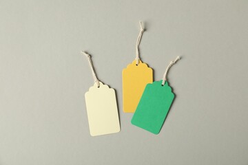 Blank tags with strings on grey background, flat lay