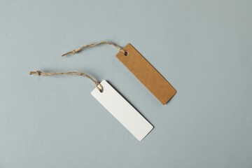 Blank tags with strings on grey background, flat lay