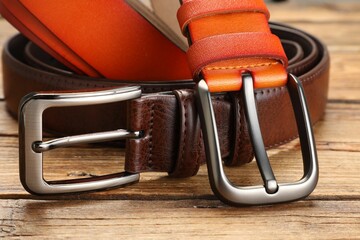Two leather belts on wooden table, closeup