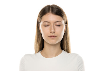 Close-up portrait of young woman with long straight light brown hair wearing white top, neutral...