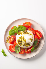 Burrata cheese caprese salad with cherry tomatoes, olive oil, pesto and seasoning. Fresh food concept