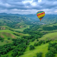 Obraz premium Colorful Hot Air Balloon Soaring Over Lush Green Valley Under Cloudy Sky