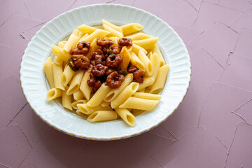 Close-up of penne pasta with shrimps on a plate, Mediterranean style with tomatoes