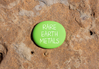 Rare earth metals symbol. Concept words Rare earth metals on beautiful green stone. Beautiful brown...