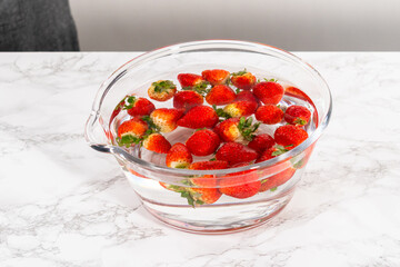 Preparing Strawberries in a Glass Mixing Bowl with Water