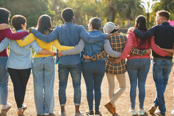 Crowd of multiracial people hugging each other at city park - Back view of multi generational community outdoor - Humanity concept