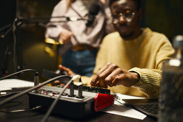 Man using mixing console for recording podcast with his colleague in studio