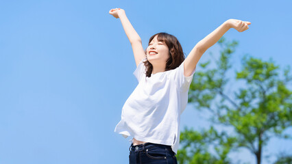 夏の青空とストレッチをする笑顔の女性