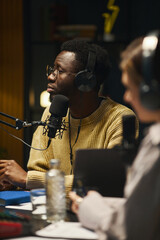 African American man in headphones sitting at table with his colleague during interview
