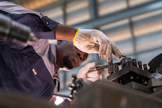 Engineer closely inspecting precision components on a metal lathe machine. Focus, technical expertise, industrial engineering, mechanical work, and manufacturing process.