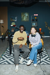 Portrait of happy young people smiling at camera while having podcast in studio