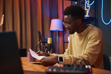 African American man sitting at his workplace and reading script before interview