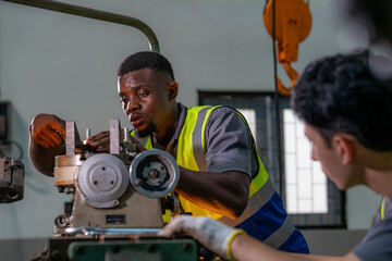 Two engineers focus on adjusting industrial machinery with precision. Teamwork, mechanical engineering, machine maintenance, technical collaboration, and industrial training.