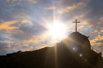 Cross against beautiful sunset over the mountains, christianity and religion concept