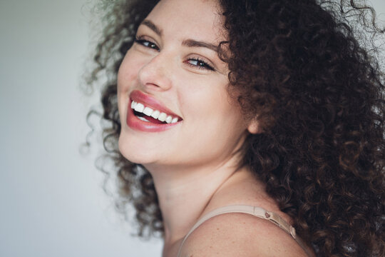 Captivating portrait of a woman radiating confidence and beauty with a charming smile and natural curly hair