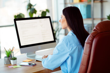Confident young professional woman working at her desk in a modern office environment, focusing on...