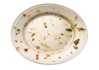 Closeup of a dirty white plate with remnants of a meal showing food scraps herbs and spices