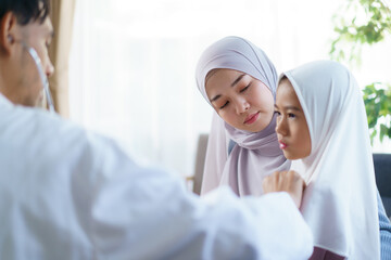 Asian muslim woman taking her daughter to see doctor in hospital.