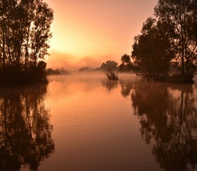 Tranquil Sunrise Over a Calm Lake With Trees and Morning Mist