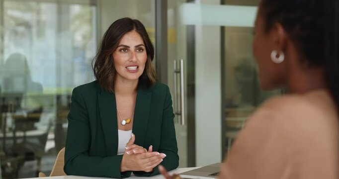 Confident Hispanic young professional woman talking to female African colleague, discussing partnership, teamwork, hiring, employment terms, giving handshake over meeting table