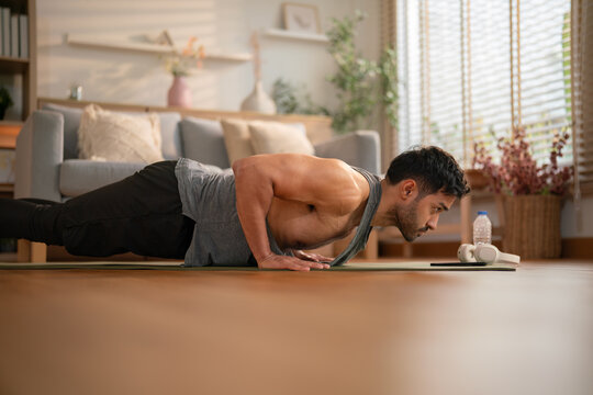 Determined young man doing push-ups during home workout