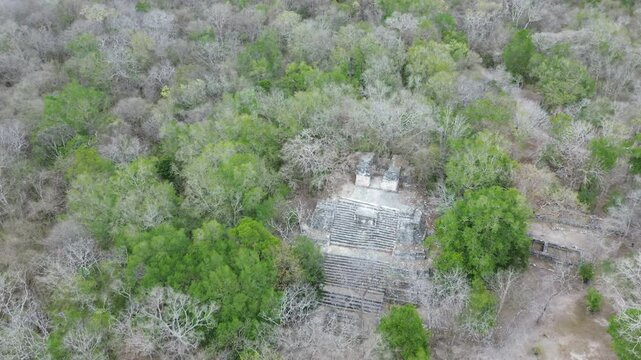 Aerial video of Mayan ruins of Coba archeological site showing a pyramid from above surrounded by the jungle.