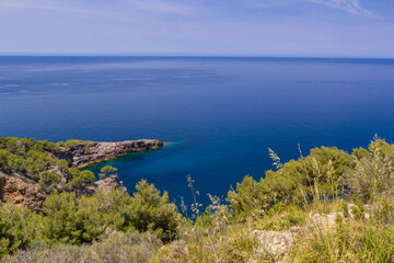 Obraz premium Soller, Balearic Islands, Spain - An incredible view of the turquoise sea and rock point with green shrubs in the foreground