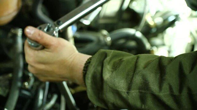 Mechanic hands methodically tighten head bolts using torque wrench. Critical engine assembly step shown in repair shop with focus on technical accuracy. Engine Repair Process. Torque wrench in hands